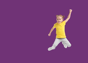 Cute girl jumping on purple background, space for text