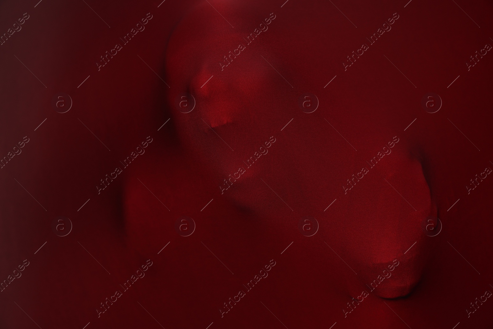 Photo of Silhouette of creepy ghost with skulls behind red cloth