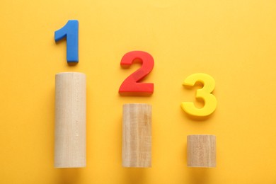 Photo of Numbers on wooden blocks against pale orange background, flat lay. Competition concept