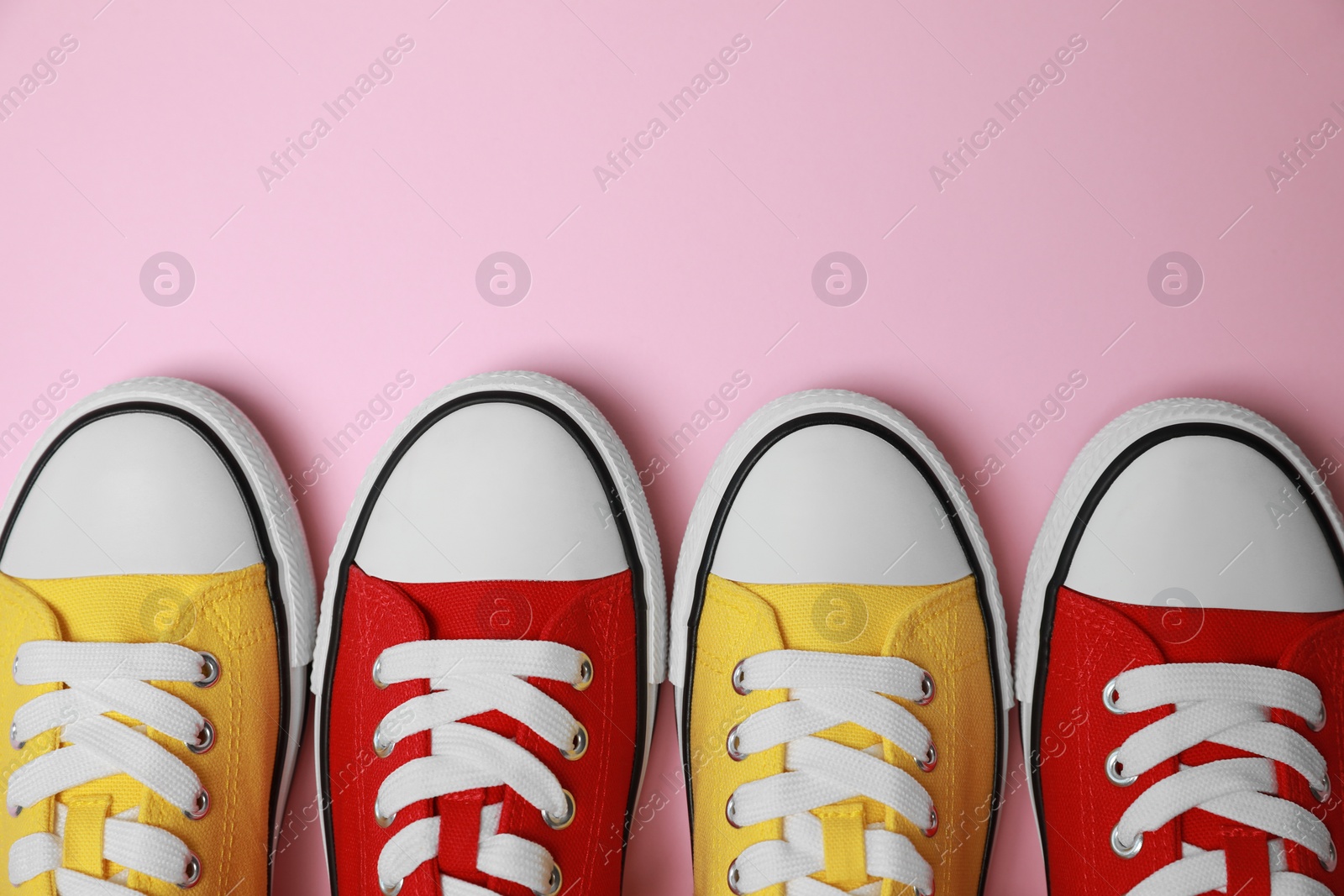 Photo of Different classic old school sneakers on pink background, flat lay. Space for text