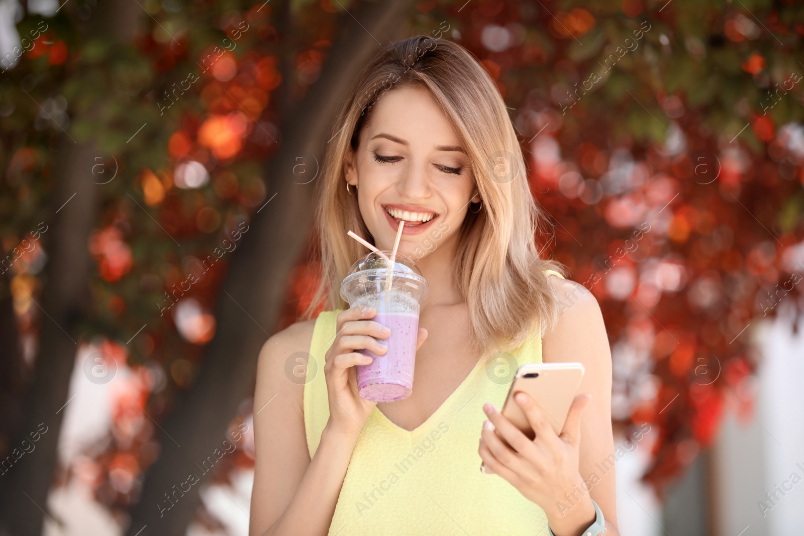 Photo of Young woman with plastic cup of healthy smoothie outdoors