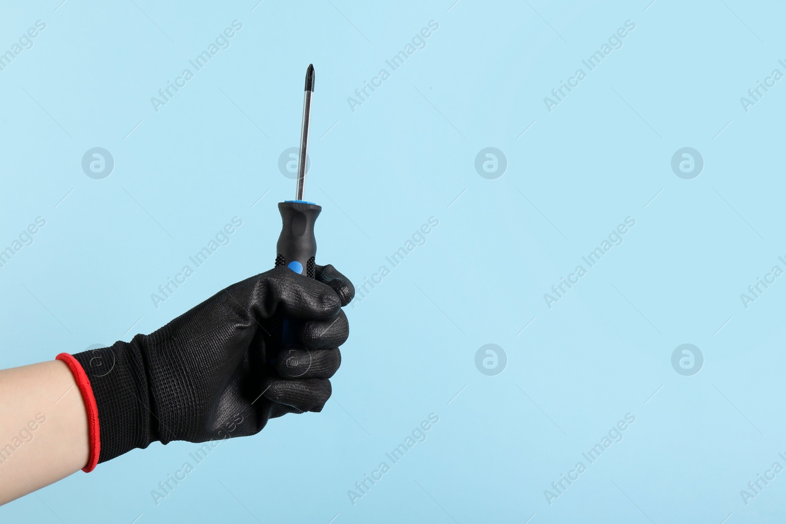 Photo of Woman holding screwdriver on light blue background, closeup. Space for text