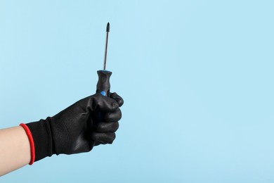 Photo of Woman holding screwdriver on light blue background, closeup. Space for text