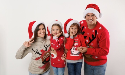 Photo of Family in Christmas sweaters and Santa hats on white background