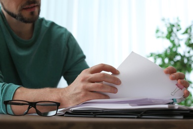 Man working with documents at table in office, closeup