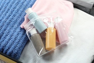 Photo of Plastic bag of cosmetic travel kit in suitcase, top view