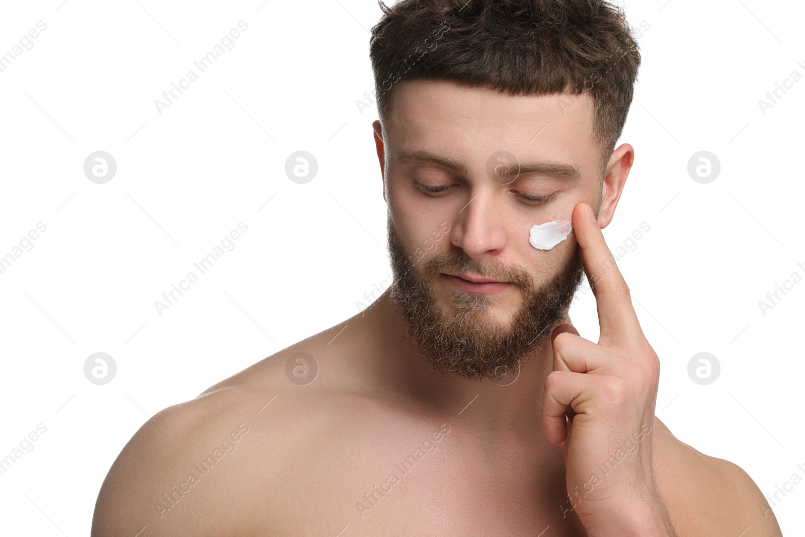 Photo of Handsome man applying moisturizing cream onto his face on white background