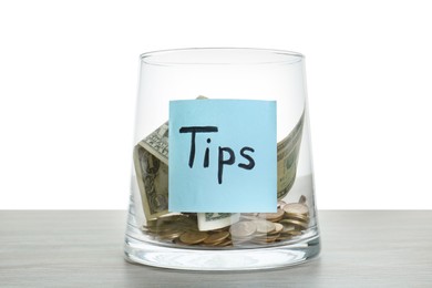 Photo of Tip jar with money on wooden table against white background