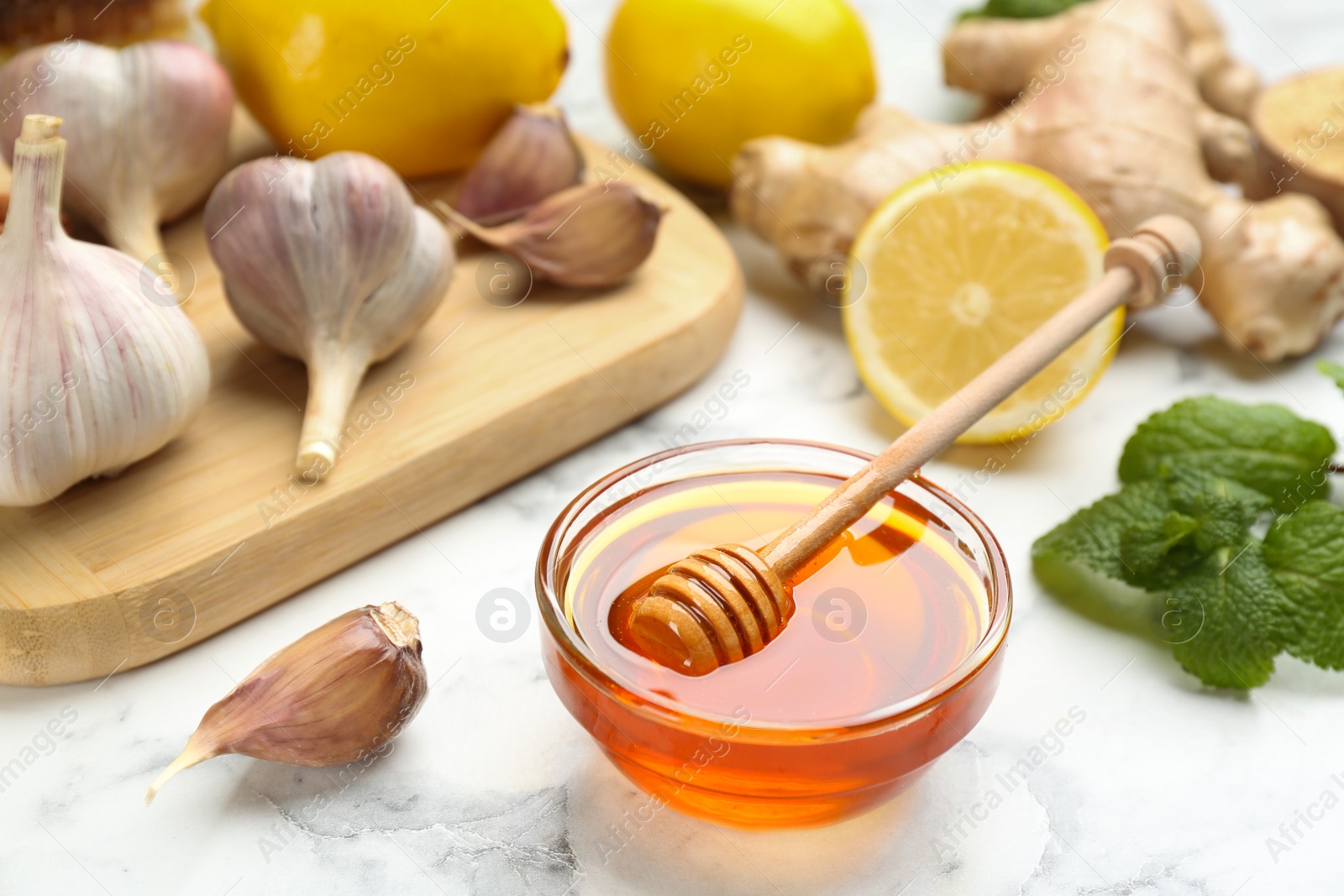 Photo of Honey and other fresh products on white marble table, closeup. Natural antibiotics