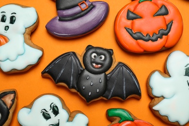 Different decorated gingerbread cookies on orange background, flat lay. Halloween celebration