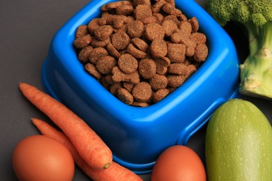 Photo of Dry pet food and products on black background, closeup