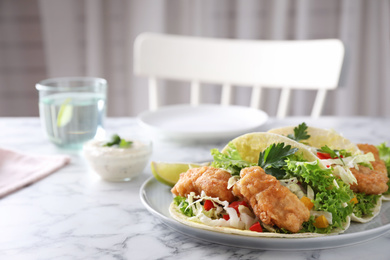 Photo of Yummy fish tacos served on white marble table, space for text