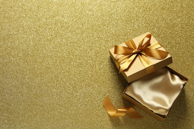 Photo of Open gift box on golden background, top view. Space for text