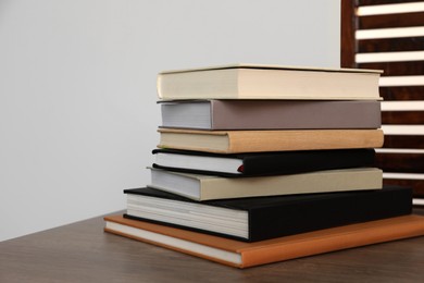 Stack of different hardcover books on wooden table indoors. Space for text