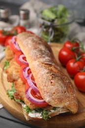 Photo of Delicious sandwich with schnitzel on grey wooden table, closeup