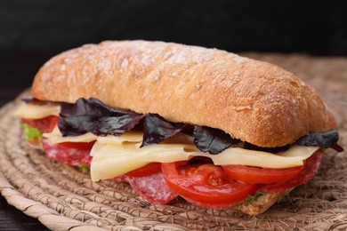 Photo of Delicious sandwich with cheese, salami, tomato on wicker mat, closeup