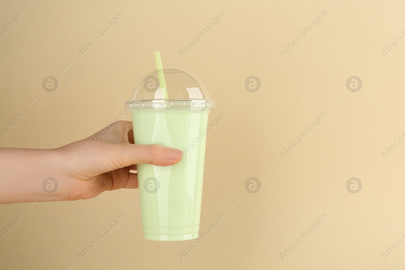 Photo of Woman with plastic cup of tasty smoothie on beige background, closeup. Space for text