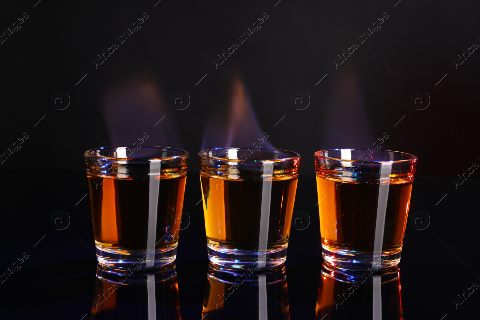 Photo of Flaming alcohol drink in shot glasses on mirror surface