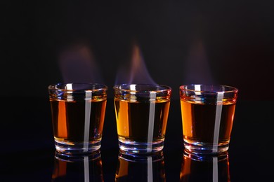 Photo of Flaming alcohol drink in shot glasses on mirror surface