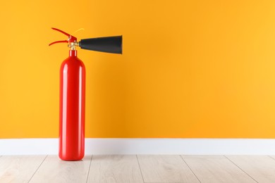 Photo of Fire extinguisher near orange wall, space for text