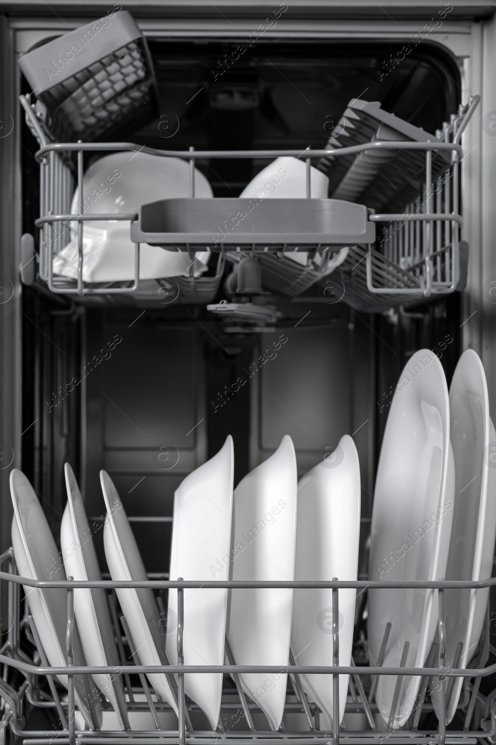 Photo of Open modern dishwasher with clean tableware, closeup