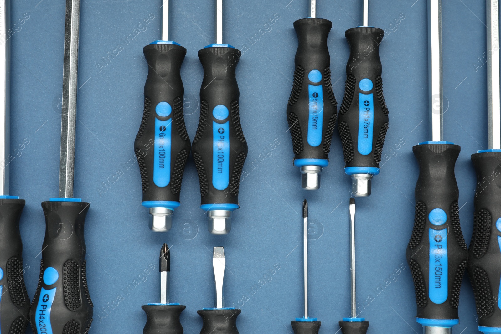 Photo of Set of screwdrivers on blue background, flat lay