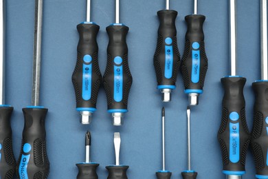 Photo of Set of screwdrivers on blue background, flat lay