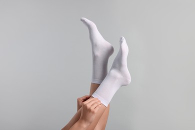 Photo of Woman in stylish white socks on light grey background, closeup