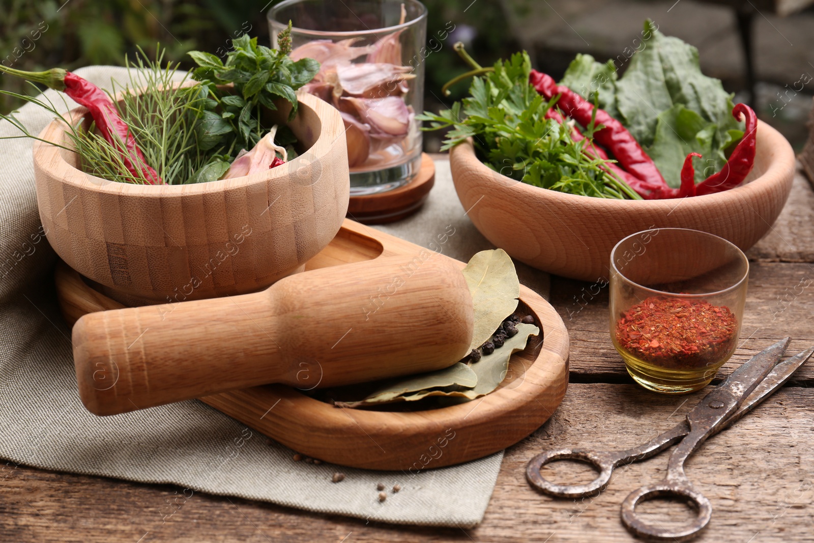 Photo of Mortar with pestle and different ingredients on wooden table outdoors