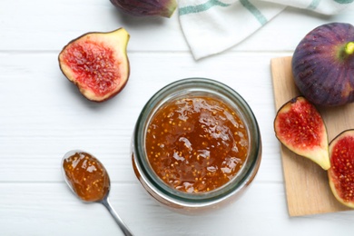 Delicious fig jam and fresh fruits on white wooden table, flat lay