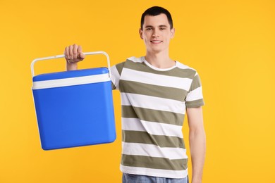 Man with blue cool box on orange background