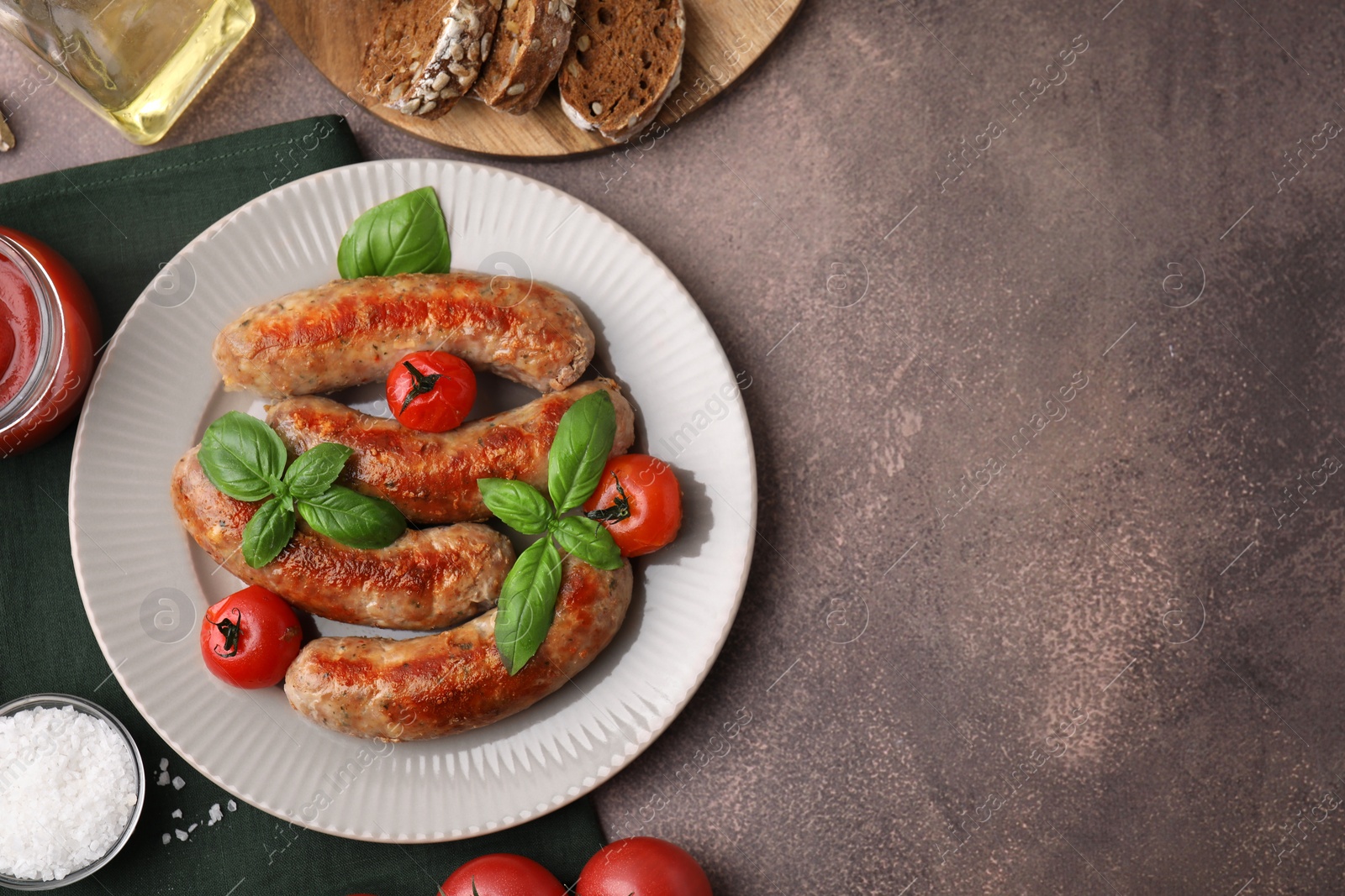 Photo of Flat lay composition with tasty homemade sausages, basil leaves and tomatoes on brown textured table. Space for text