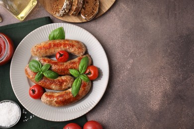 Photo of Flat lay composition with tasty homemade sausages, basil leaves and tomatoes on brown textured table. Space for text