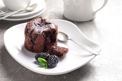 Plate of delicious fresh fondant with hot chocolate and blackberries on table. Lava cake recipe