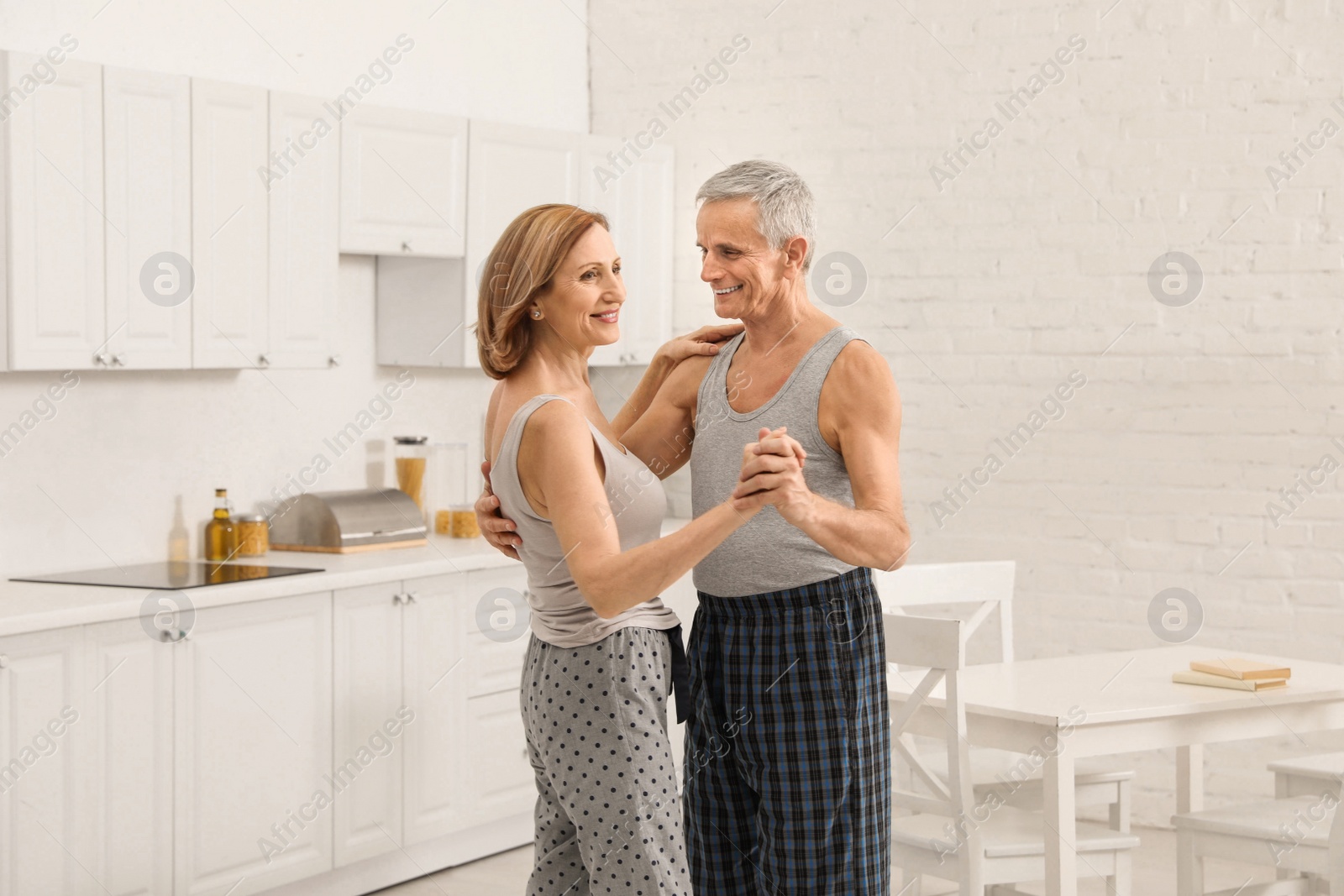 Photo of Happy senior couple dancing together in kitchen