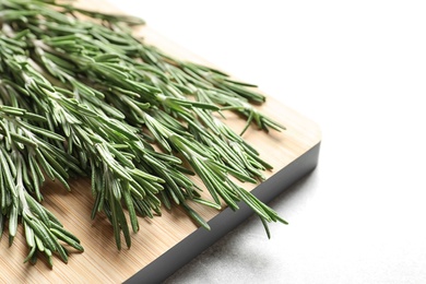 Wooden board with fresh rosemary twigs on table, closeup