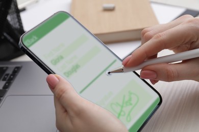 Image of Electronic signature. Woman using stylus and mobile phone at white wooden table, closeup