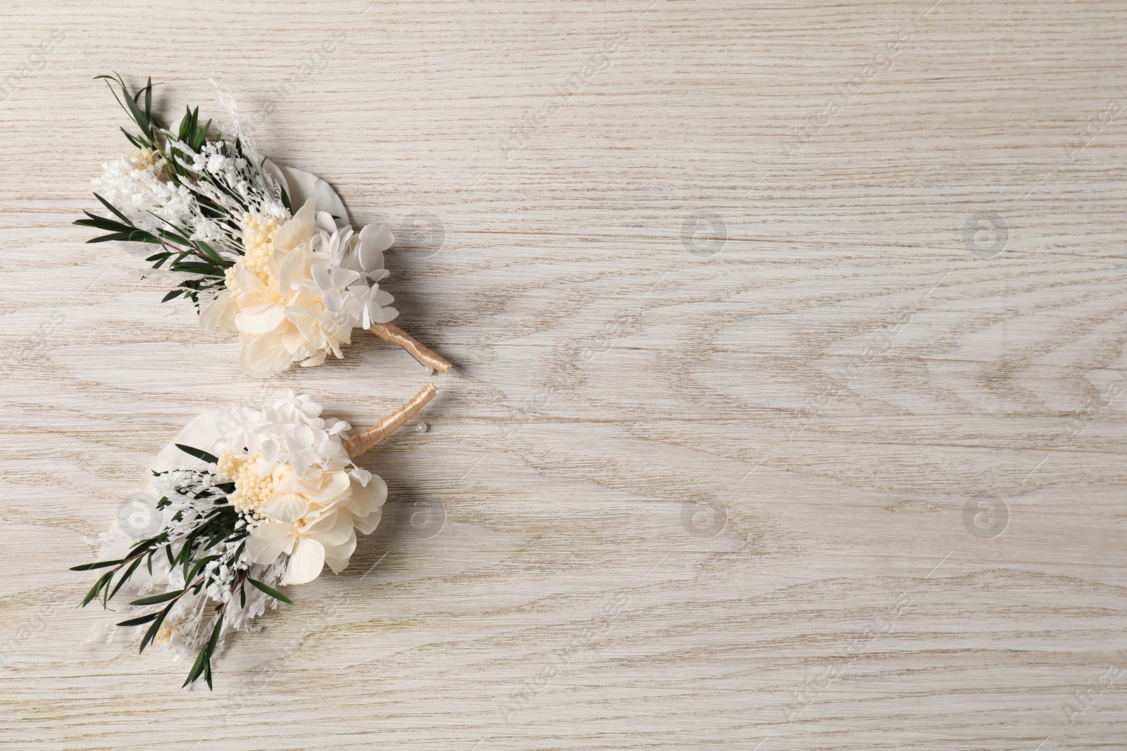 Photo of Stylish boutonnieres on white wooden table, top view. Space for text