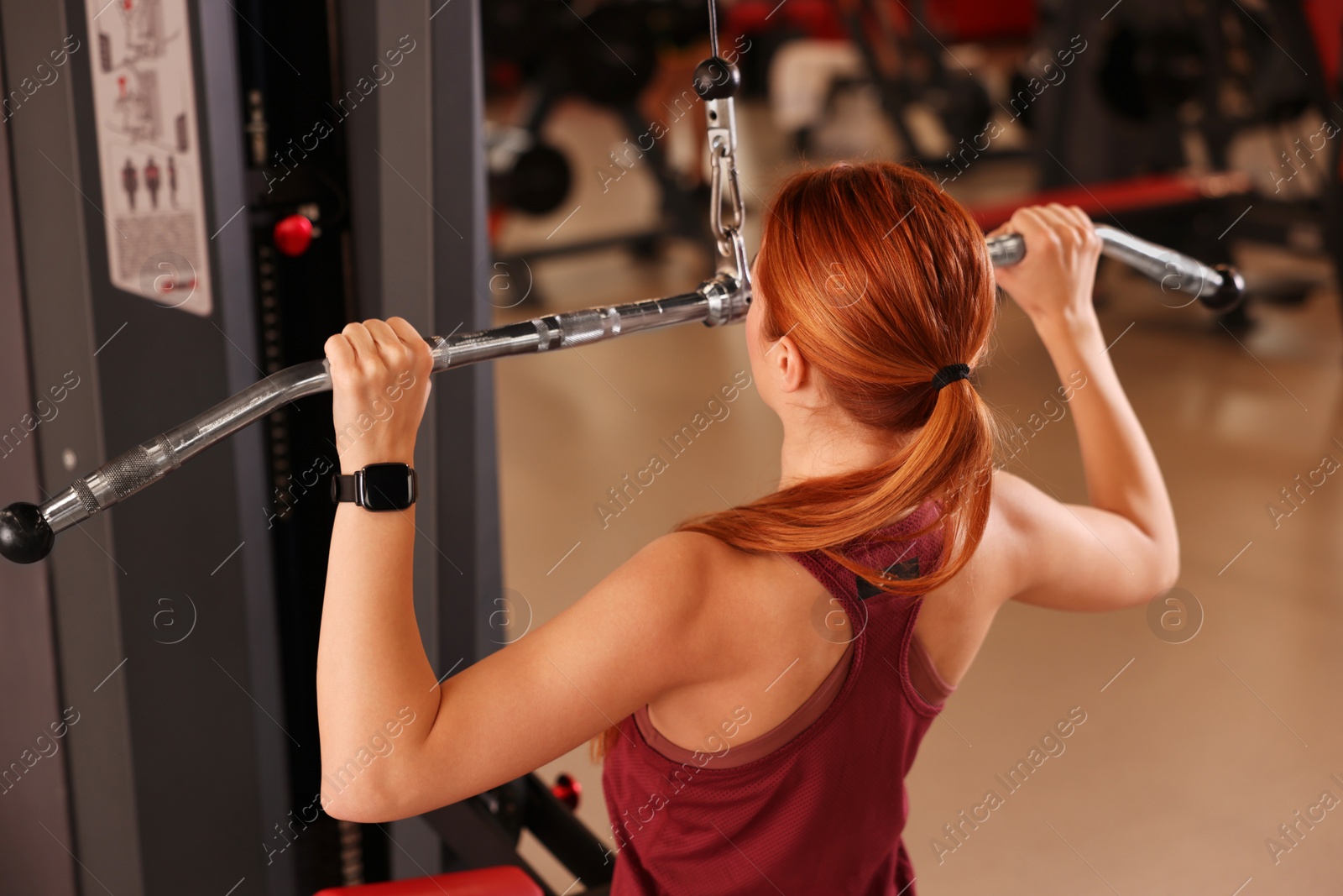 Photo of Young woman training in modern gym, back view