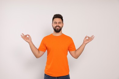 Photo of Young man meditating on white background. Zen concept