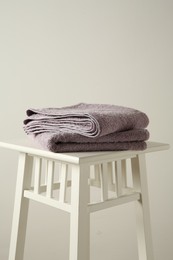 Violet towels on stool against white wall