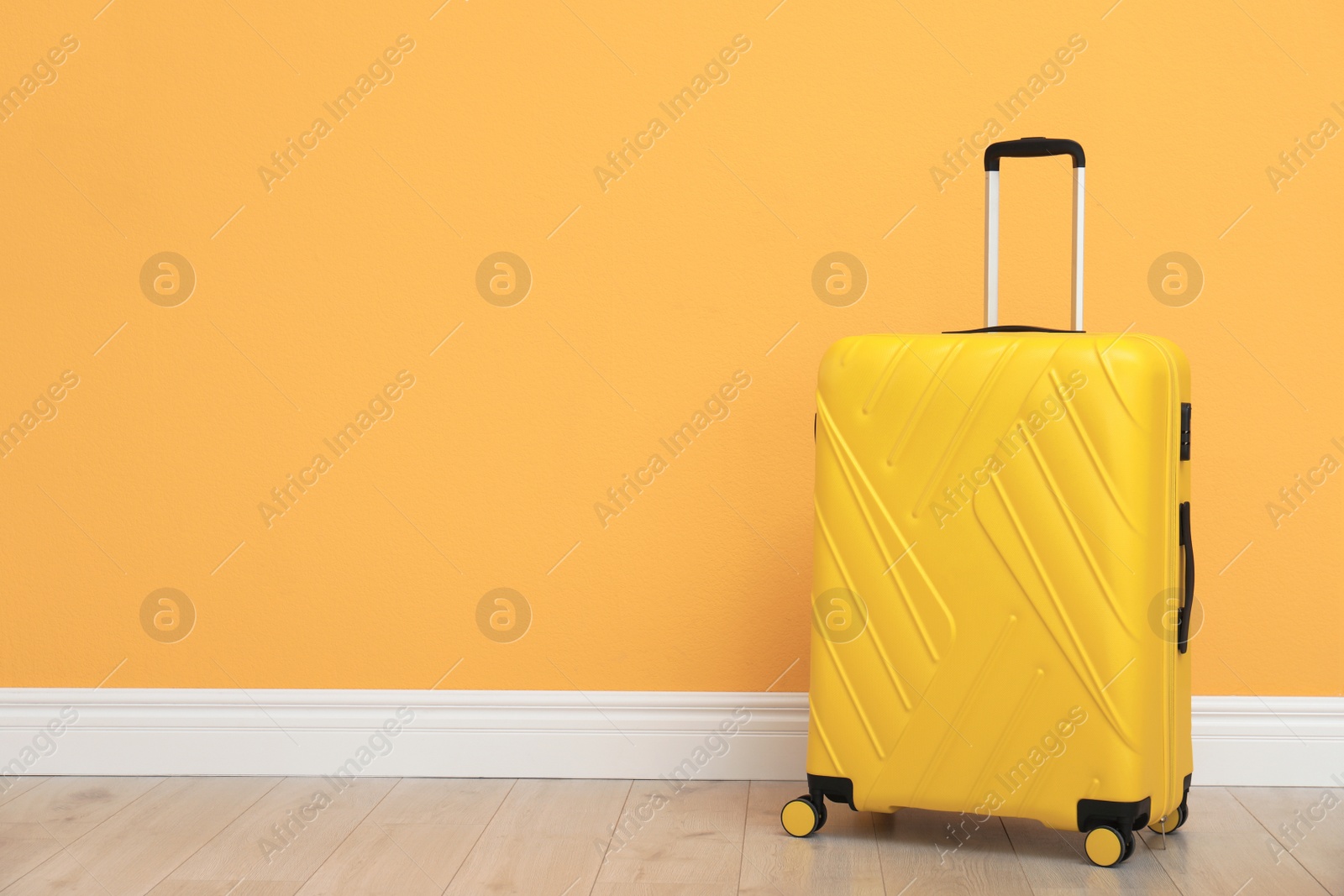 Photo of Suitcase packed for travel on floor near color wall. Space for text