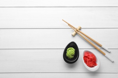 Photo of Swirl of wasabi paste, pickled ginger and chopsticks on white table, flat lay. Space for text