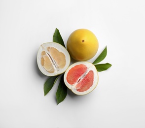 Photo of Fresh cut and whole pomelo fruits with leaves on white background, top view