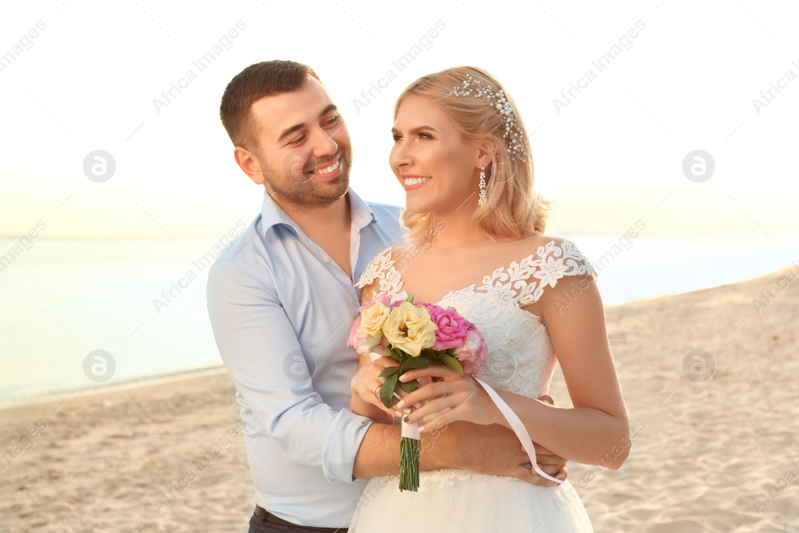 Photo of Wedding couple. Bride and groom hugging on beach at sunset