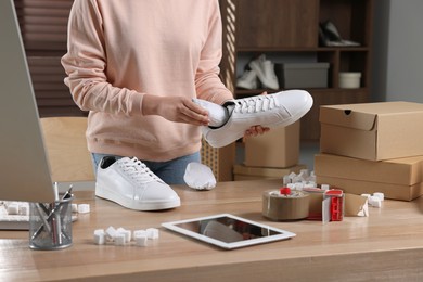 Photo of Seller packing shoes at workplace, closeup. Online store