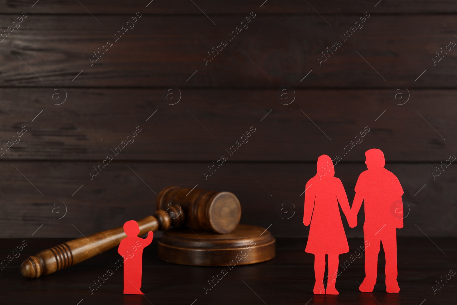 Photo of Gavel, paper figures of couple and lonely kid on wooden table. Child adoption concept
