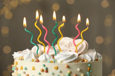 Photo of Beautiful birthday cake with burning candles on blurred background, closeup