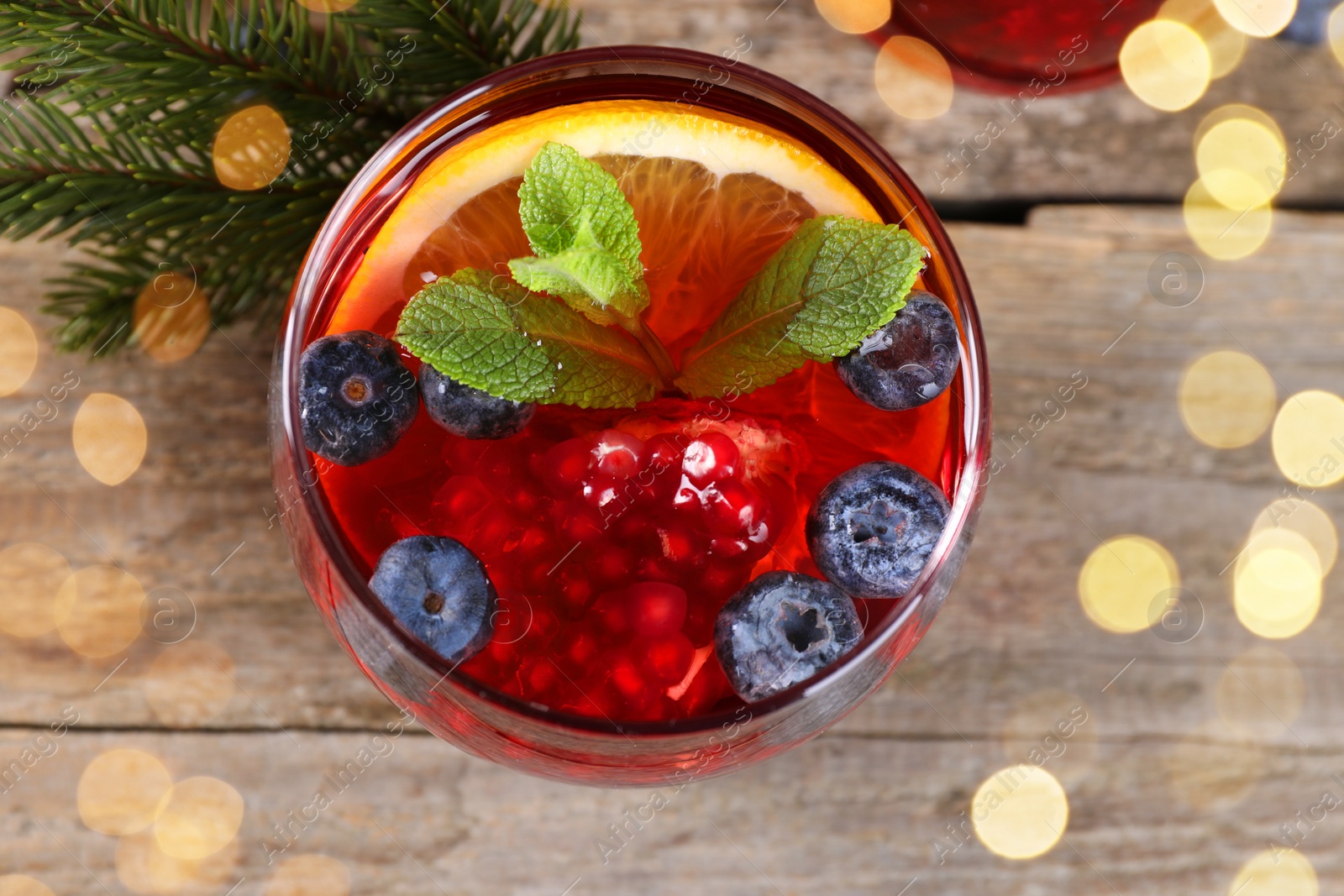 Photo of Aromatic Christmas Sangria drink in glass on wooden table, top view