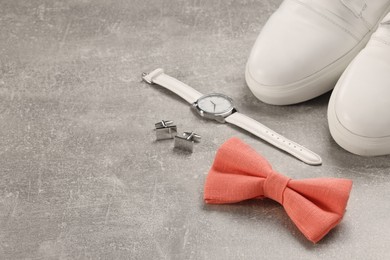 Photo of Stylish pink bow tie, wristwatch, shoes and cufflinks on light grey background, space for text